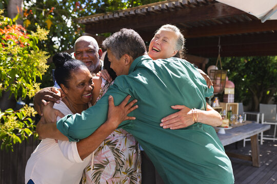 Celebrating friendship, diverse senior friends embracing joyfully at outdoor gathering, sharing happ