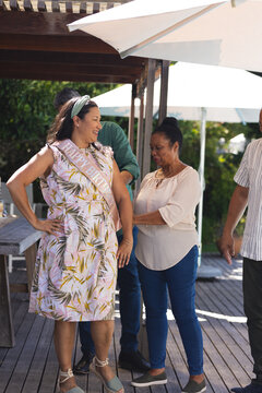 Celebrating birthday, joyful woman wearing sash surrounded by diverse senior friends outdoors