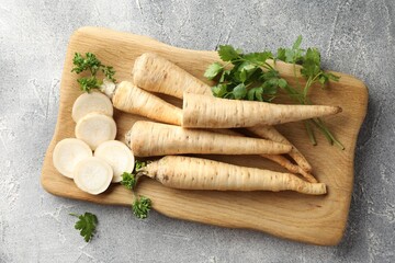 Parsley roots and leaves on grey table, top view
