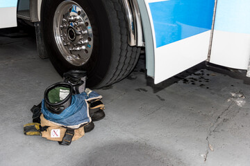 A blue and white fire truck with the door open and fire fighter boots and pants at the ready on the floor next to the truck door.