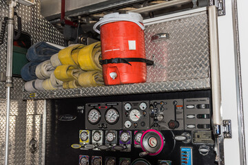 Detail of a fire truck, including, gauges, coiled fire hoses, and red water cooler.