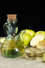 Apple cider vinegar in a glass vinegar bowl among apples