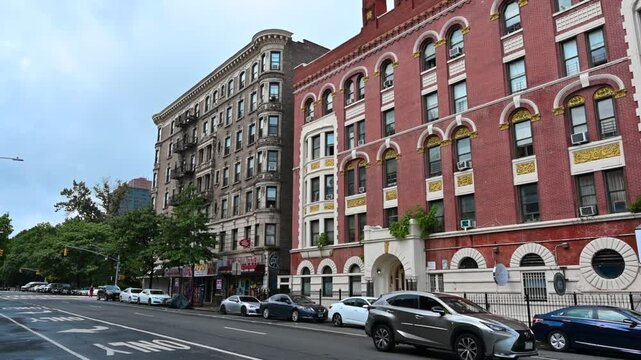 New York, United States, August 18, 2024. Street view in Harlem neighborhood. Old buildings overlook the street, cars. Pan motion.