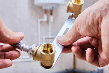 Close-up of hands connecting flexible hose to plumbing system.