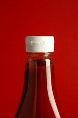 Tasty ketchup in bottle on red background, closeup