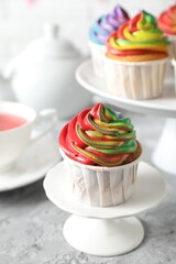 Delicious cupcake with colorful cream on grey textured table, closeup