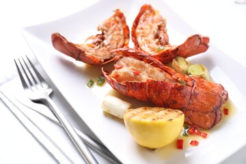 Delicious lobster tails with lemon and green onion on white table, closeup
