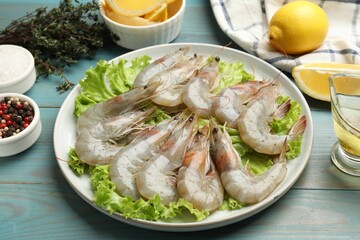 Fresh raw shrimps and spices on light blue wooden table, closeup