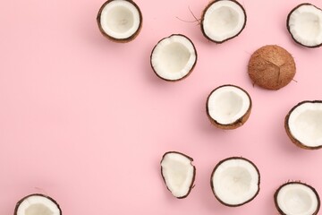 Pieces of cracked coconuts on pink background, flat lay. Space for text
