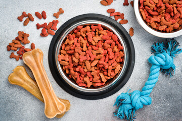 Dry pet food in a bowl. Top view, on a gray stone background.