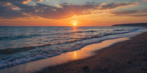 sunset over calm ocean waves with a sandy beach and clouds reflecting warm colors in the sky
