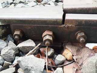 A detailed view of a railway track section, showcasing metal bolts, rails, and surrounding gravel.