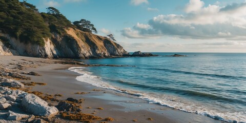 Coastal landscape with sandy beach rocky shoreline cliffs ocean waves and blue sky with clouds during calm weather in the afternoon