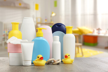 Baby cosmetic products and rubber ducks on table in room. Space for text