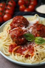 Delicious pasta with meatballs, basil and cheese on brown textured table, closeup