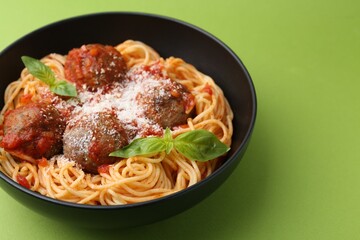 Delicious pasta with meatballs and cheese in bowl on green table, closeup