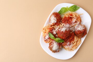 Delicious pasta with meatballs, basil and cheese on beige table, top view. Space for text