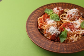 Delicious pasta with meatballs, cheese and basil on green table, closeup. Space for text