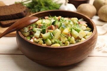 Delicious okroshka soup with kvass and ingredients on white wooden table, closeup
