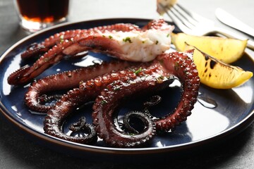 Fried octopus with herb sauce and lemon on grey table, closeup