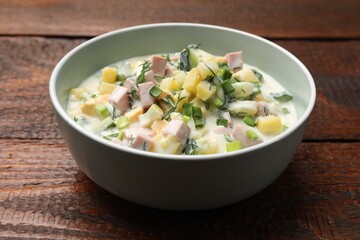 Delicious okroshka soup in bowl on wooden table, closeup