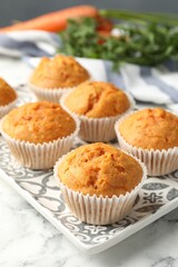 Tasty carrot muffins on white marble table, closeup