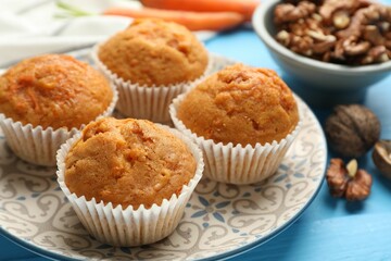 Tasty carrot muffins and walnuts on light blue wooden table, closeup