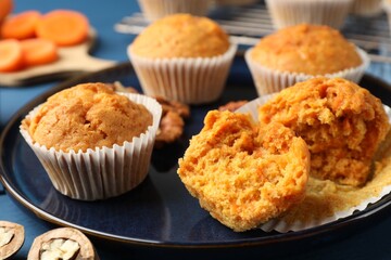 Tasty carrot muffins and walnuts on blue wooden table, closeup