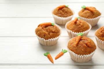 Tasty carrot muffins on white wooden table, closeup. Space for text
