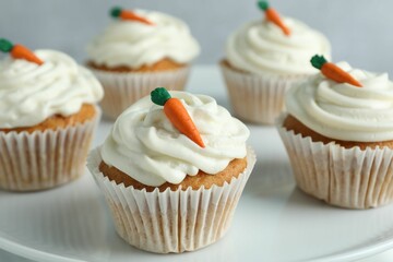 Delicious carrot cupcakes on plate against grey background, closeup
