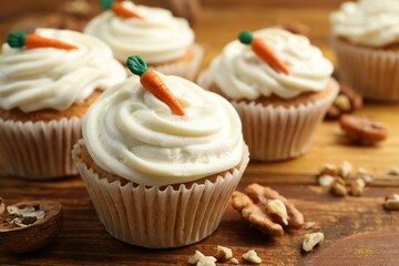 Delicious carrot cupcakes and walnuts on wooden table, closeup