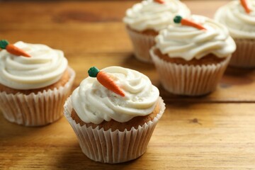 Delicious carrot cupcakes on wooden table, closeup