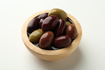Tasty marinated olives in bowl on white table, closeup