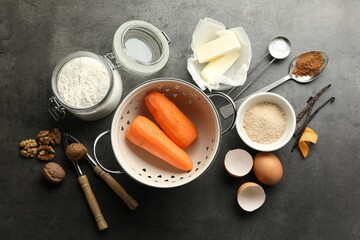 Different ingredients for making carrot cake and kitchenware on dark textured table, flat lay