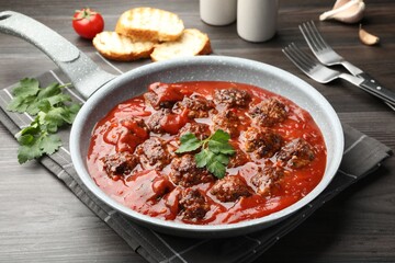 Delicious meatballs with tomato sauce served on wooden table, closeup