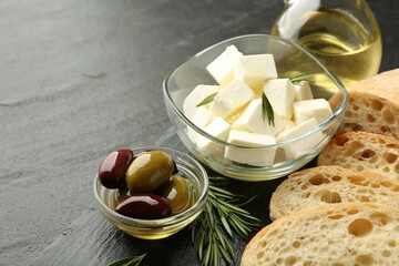 Delicious marinated olives, bread and feta cheese served on black table, closeup. Space for text