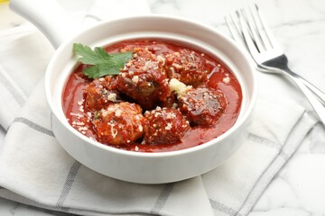 Delicious meatballs with tomato sauce, parmesan cheese and parsley served on white table, closeup