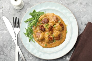 Delicious meatballs with gravy cream sauce, herbs and arugula served on grey table, flat lay