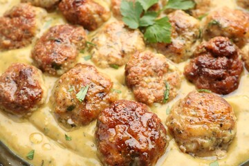 Delicious meatballs with gravy cream sauce and herbs, closeup