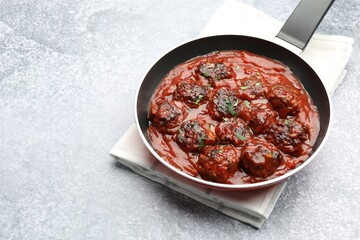 Delicious meatballs with tomato sauce and herbs in on grey table. Space for text