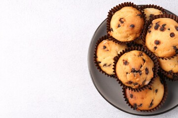 Delicious muffin with chocolate chips on light grey table, top view. Space for text