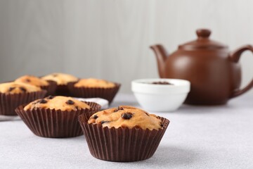 Delicious muffin with chocolate chips on light grey table, closeup