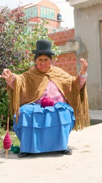vertical old woman cholita aymara woman in pollera working with wool in the yard of her house in the city of la paz bolivia - concept of handicraft work