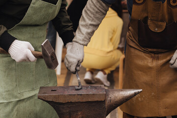 The blacksmith forging the metal on the anvil in smithy