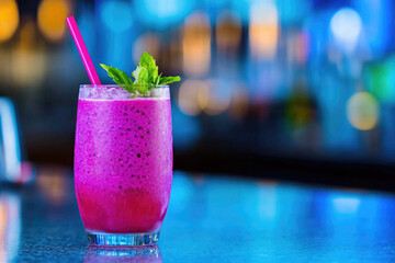 Refreshing pink cocktail with mint and vibrant blurred background at a bar