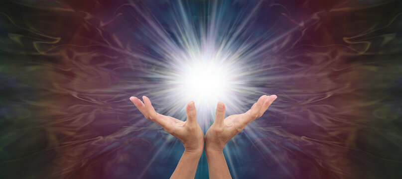 Vibrant high resonance healing energy starlight wall art - female healer's hands cupped and open creating light in the darkness with copy space for spiritual message
