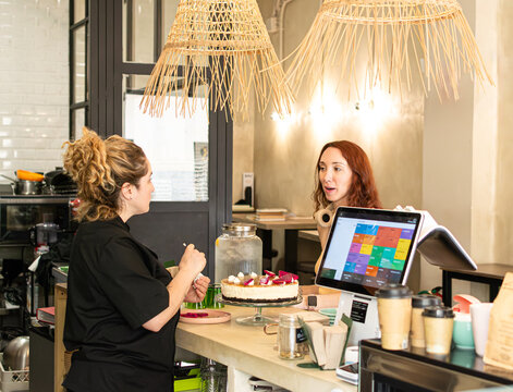Female vegan coffee shop owner serving a customer at the counter