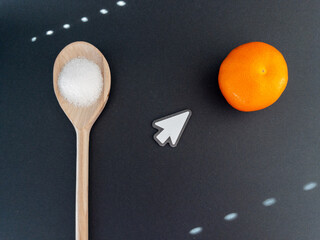 Wooden spoon with sugar and tangerine on black background