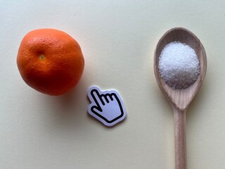 Wooden spoon with sugar and orange on yellow background