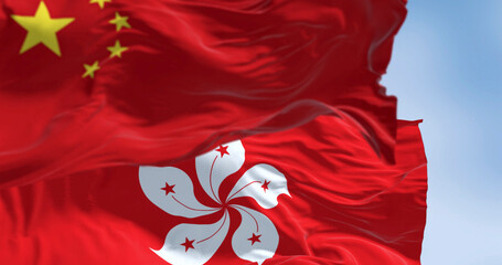 Flags of Hong Kong and China waving in the wind on a clear day